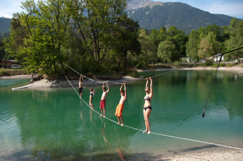5 Personen stehen auf einer Waterline über einem See mit Halteseil